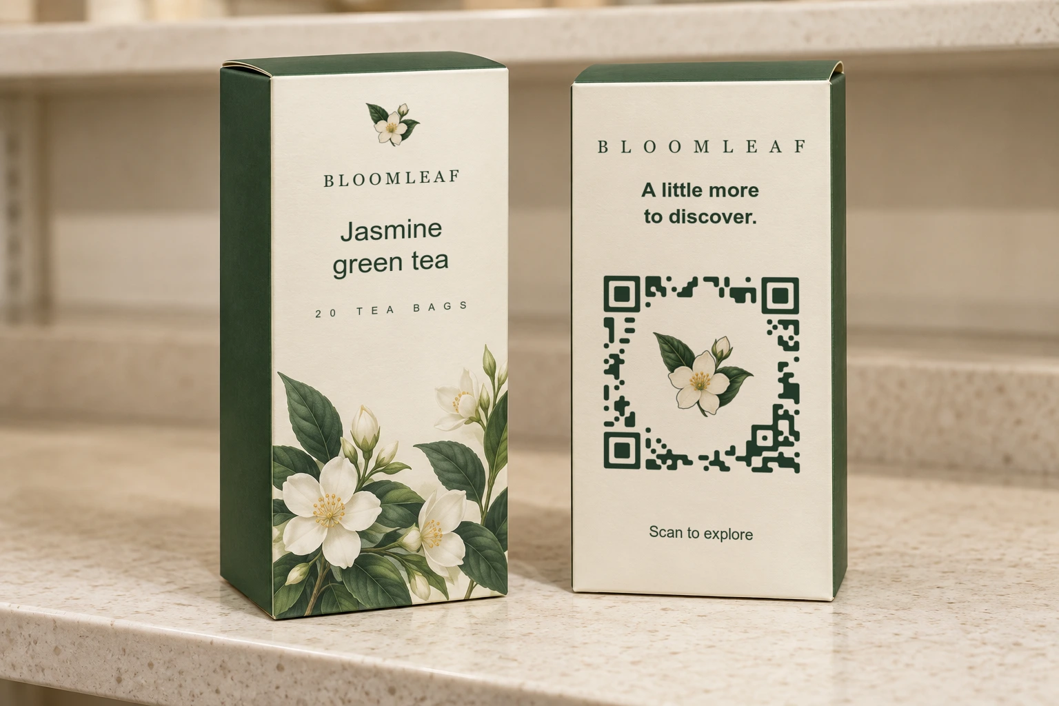 Two cream and green Bloomleaf tea cartons, with a jasmine emblem on the front and a matching botanical QR on the back panel.